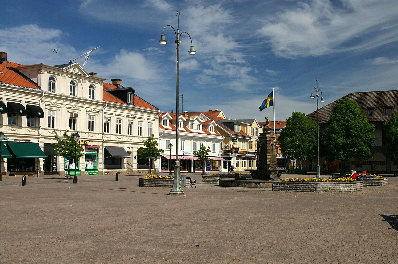 Öppet torg i Falköping omgivet av äldre stadshus och gatubelysning.