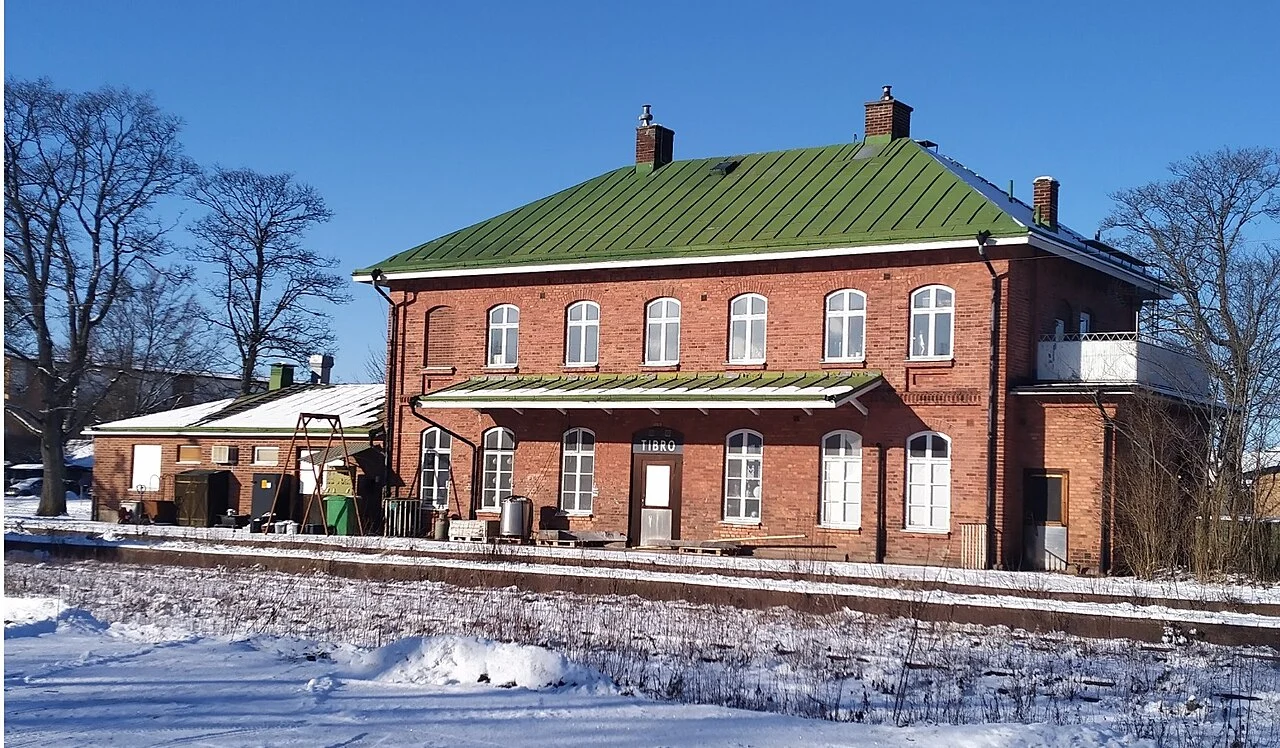 Tibros röda stationshus med grönt tak i ett vinterlandskap.