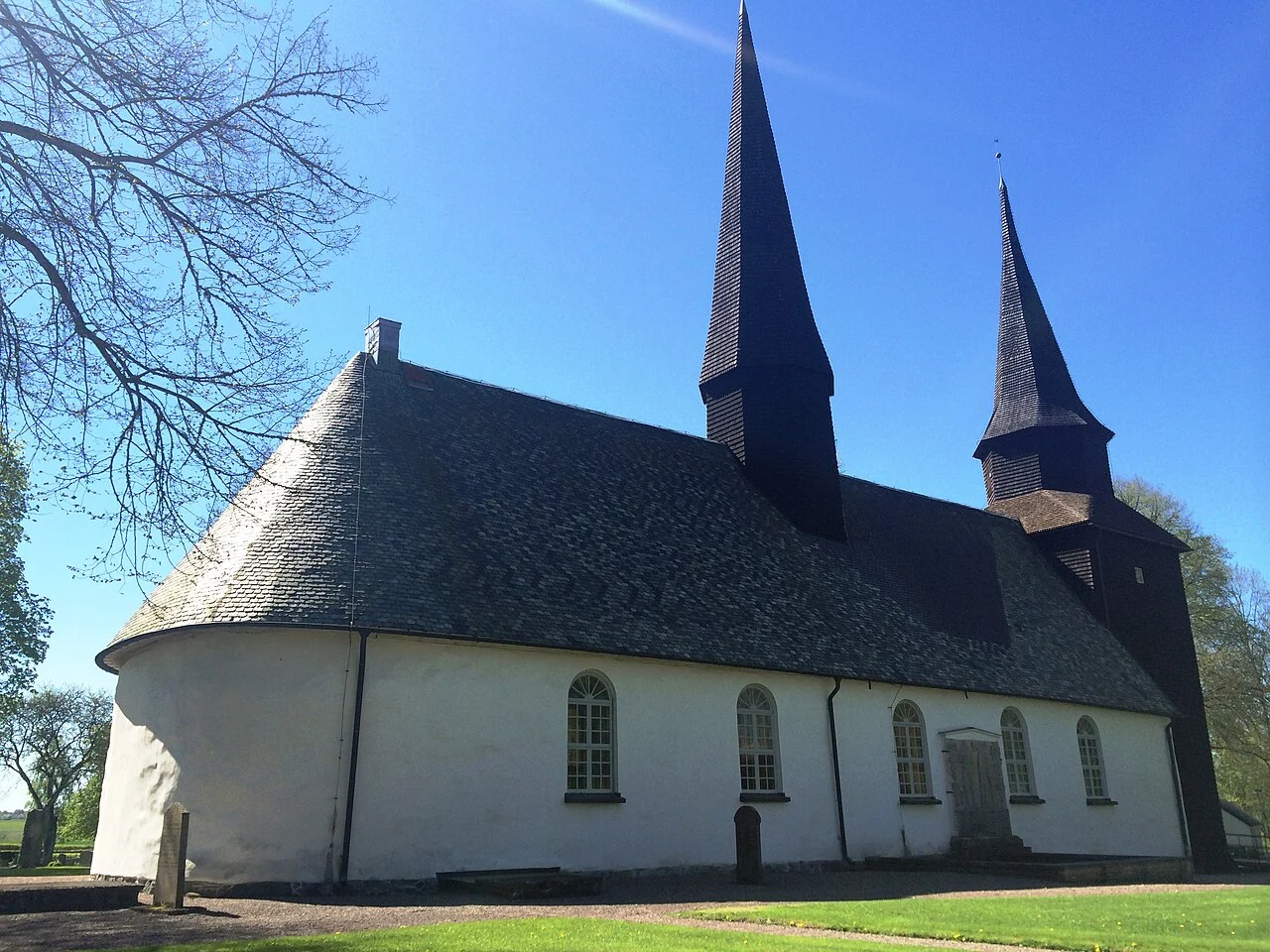 Levene kyrka i Vara kommun med vit fasad, mörkt tak och två torn.